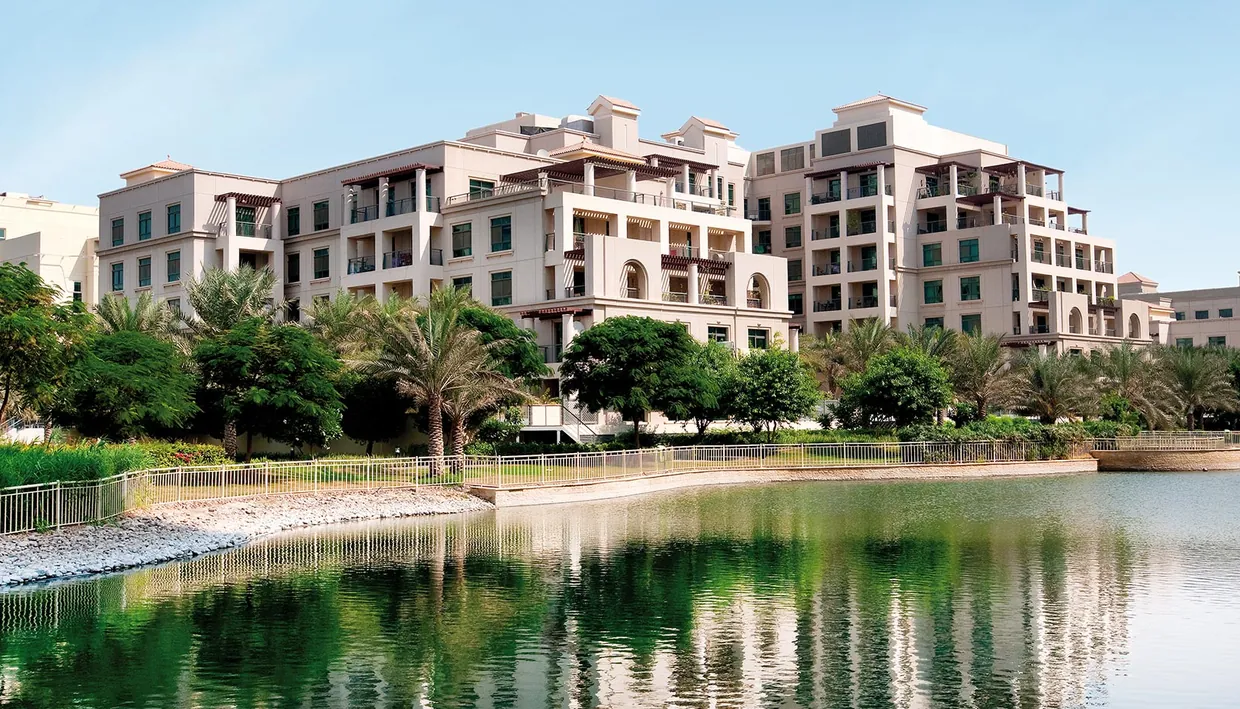 Lakeside landscaping and mid-rise residential buildings at Emaar The Greens in Dubai